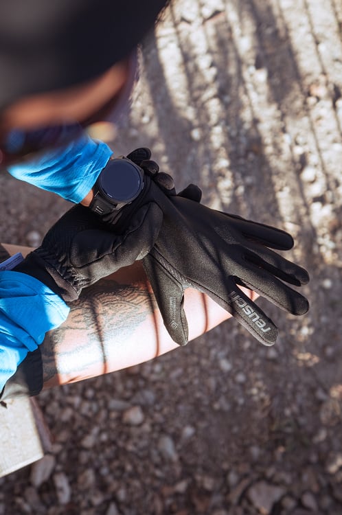 Person zieht atmungsaktive schwarze Reusch-Handschuhe beim Outdoor-Sport an